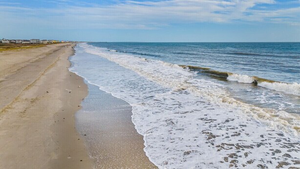 Una playa con arena y olas suaves.
