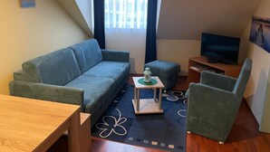 A compact living space with a sofa, a small table, a television, and a chair.