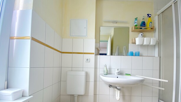 Et badeværelse med toilet, håndvask og bruseområde.