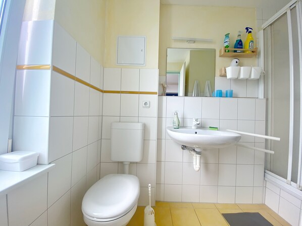 Een badkamer met toilet, wastafel en douche.