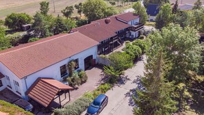 A two-story building with a red-tiled roof, a covered porch, and a car parked in front.