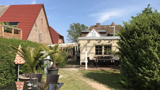 A patio with outdoor furniture, a covered seating area, and a view of a house with a red roof. - Hochzeitsberg - Double room / Apartment "Tromsö" in Breege (Breege)