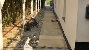 A covered walkway with a gravel path, a metal bench, and a gate leading to a building. - Hochzeitsberg - Double room / Apartment "Tromsö" in Breege (Breege)