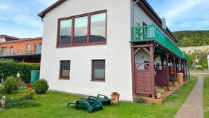 A two-story building with a balcony, a garden area with outdoor furniture, and a pathway leading to the entrance. - Apartments Stadtmitte - Apartment 3 (Sassnitz)