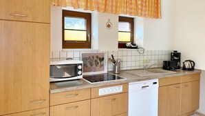 A kitchen with wooden cabinets, a microwave, a dishwasher, and a coffee maker. - Apartments Stadtmitte - Apartment 3 (Sassnitz)