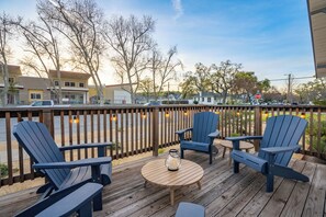 Une terrasse avec quatre fauteuils Adirondack, une table ronde en bois et une bougie.