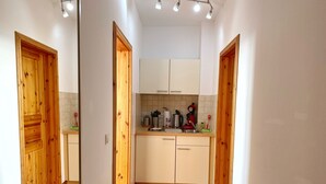 A narrow hallway with wooden doors and a kitchen area.
