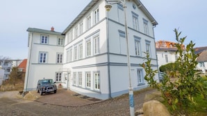 A multi-story building with a cobblestone driveway and a parked car. - Seaside Appartements, "yellow" (Sassnitz)