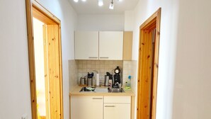 A compact kitchen with white cabinets, a sink, and a coffee machine. - Seaside Appartements, "yellow" (Sassnitz)