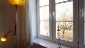 Una habitación con ventana, lámpara de pie y candelabro.
