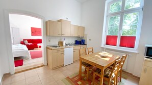 Una cocina compacta con comedor, un sofá rojo y una ventana con persianas.