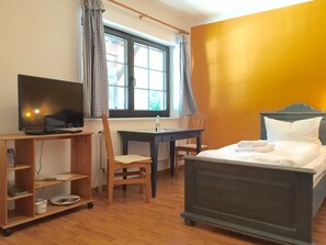 A room with a bed, a desk with a computer, a chair, and a window with curtains. - Landpension Dubnitz, double room 6 (Sassnitz)
