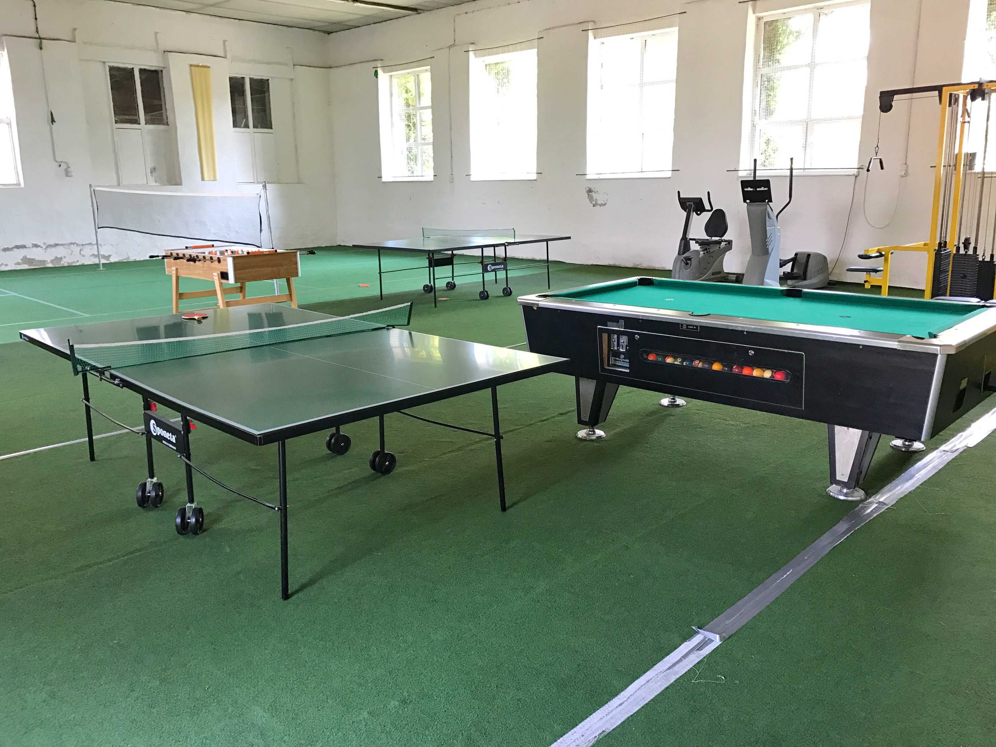 A billiards room with a pool table, a foosball table, and a table tennis table.