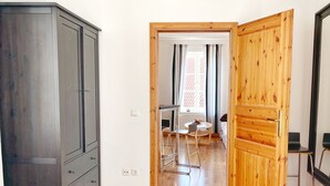 A hallway with a wooden wardrobe, a dining area with a table and chairs, and a window with curtains. - Seaside Apartments, "Brown" (Sassnitz)