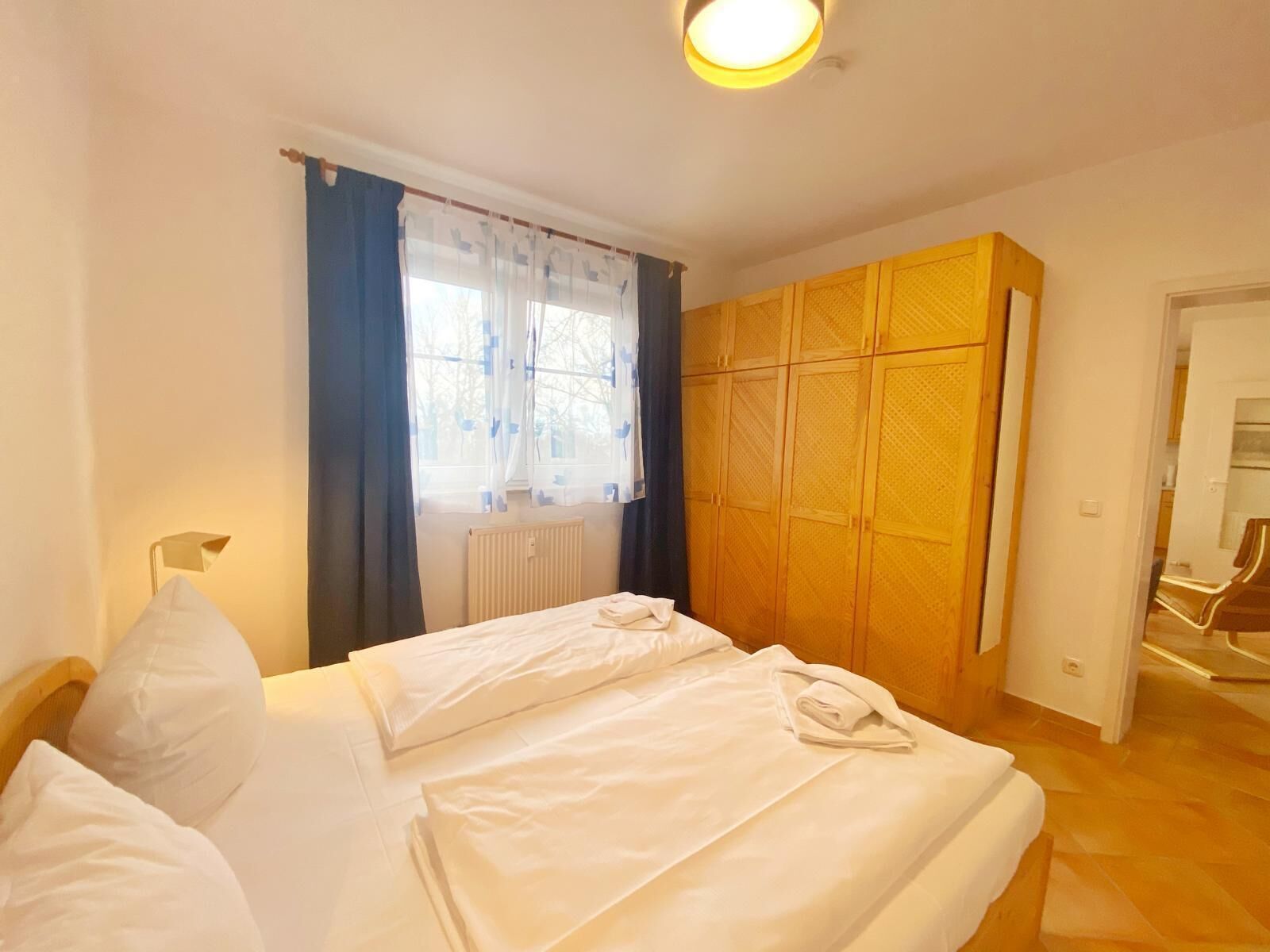 Ein Hotelzimmer mit Bett, Schrank, Heizkörper und einem Vorhangfenster.