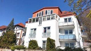 En flervåningsbostadsbyggnad med balkonger och ett rött tak.
