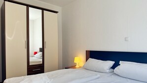 Ein Hotelzimmer mit einem Bett, einem Kleiderschrank und einem Nachttisch mit Lampe.