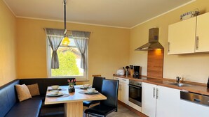 Eine kompakte Küche mit Essbereich, darunter ein Holztisch, Stühle und ein eingebauter Backofen.