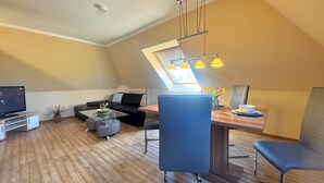 Un appartement moderne de style « loft », comprenant un coin repas, un canapé, un téléviseur et une lucarne.