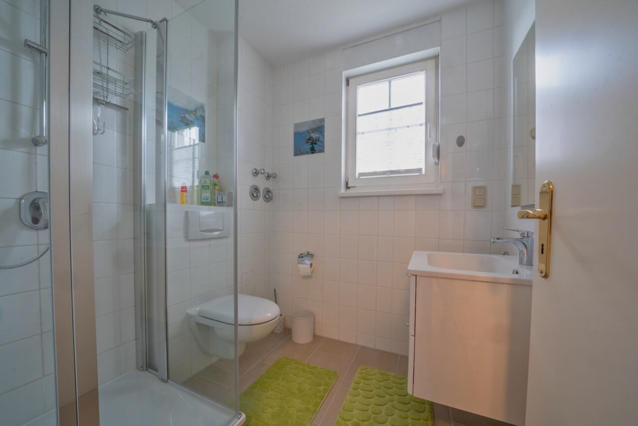 Ein Badezimmer mit Duschkabine, Toilette, Waschbecken und einem kleinen Fenster.