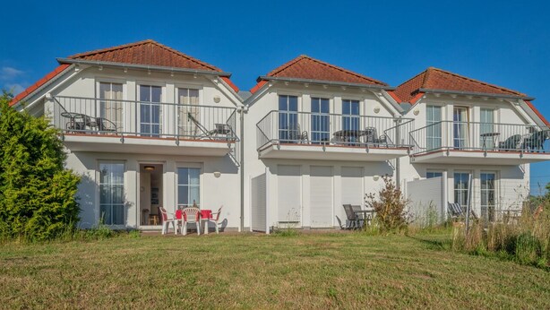 A two-story residential building with a red-tiled roof, large windows, and balconies. - Vacation apartment Neddesitz No. 51 (Neddesitz)