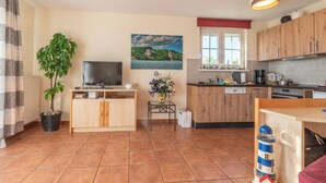 A compact kitchen with wooden cabinets, a dining area, a television, and a potted plant. - Vacation apartment Neddesitz No. 51 (Neddesitz)