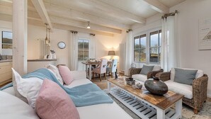 A cozy living room with a sofa, a coffee table, and a dining area with chairs and a table. - Semi-detached house Freyh II (Lohme OT Ranzow)