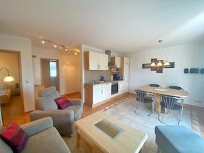 A modern apartment with a living room, dining area, and kitchen. - Ferienwohnung 2, Am Hochzeitsberg 3A (Breege)