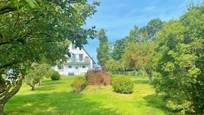 A house with a white exterior, surrounded by a well-maintained lawn and various trees. - Ferienwohnung 2, Am Hochzeitsberg 3A (Breege)