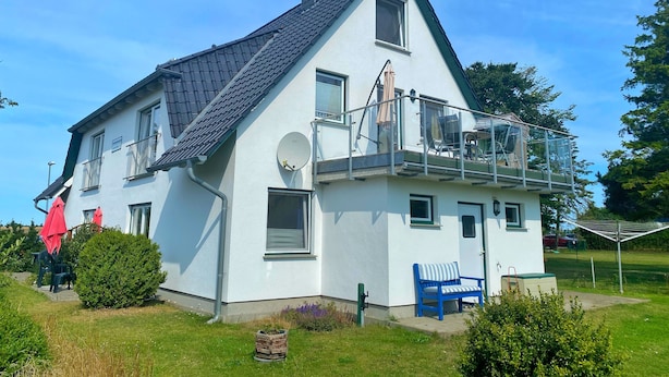 A two-story house with a balcony, a satellite dish, and a small garden area. - Ferienwohnung 2, Am Hochzeitsberg 3A (Breege)