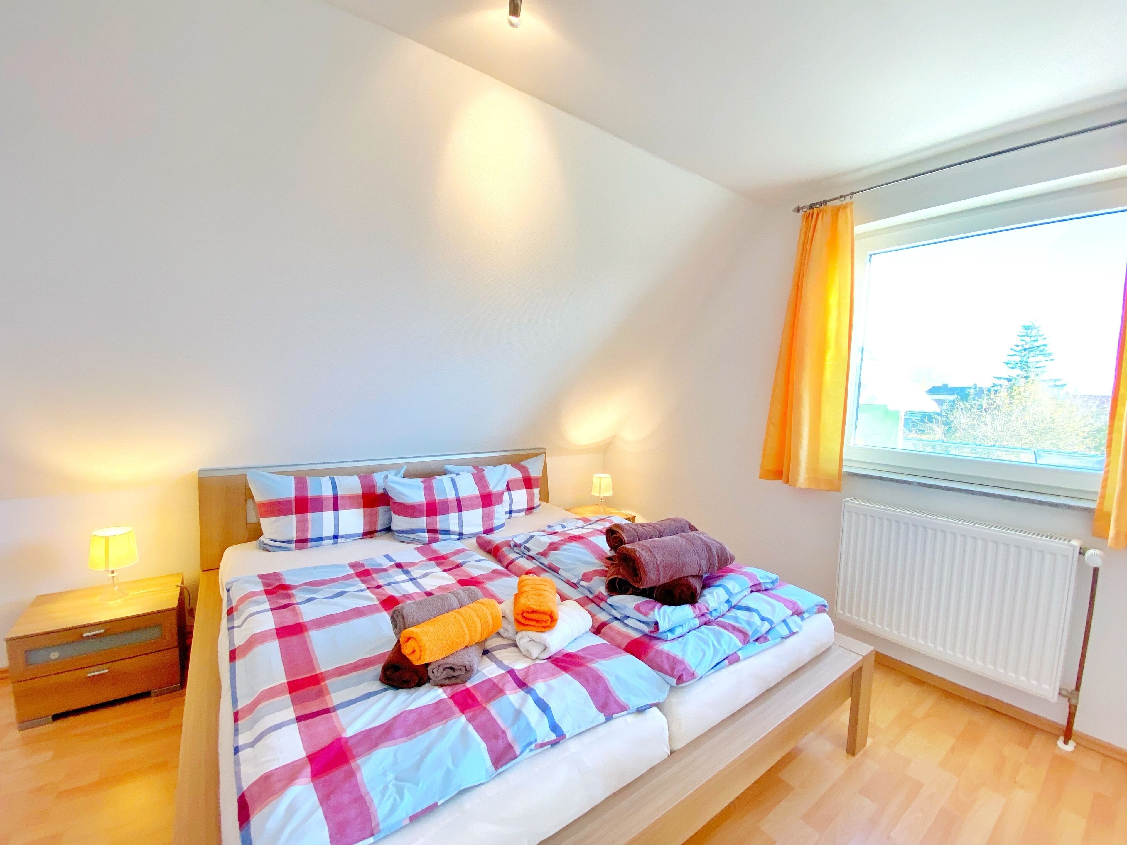 A bedroom with a bed, a nightstand, a lamp, and a window with curtains.