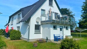 Une maison à deux étages avec un balcon, une antenne parabolique et un petit jardin.