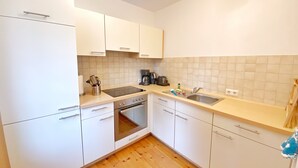 A modern kitchen with white cabinets, a stainless steel sink, and a built-in oven.