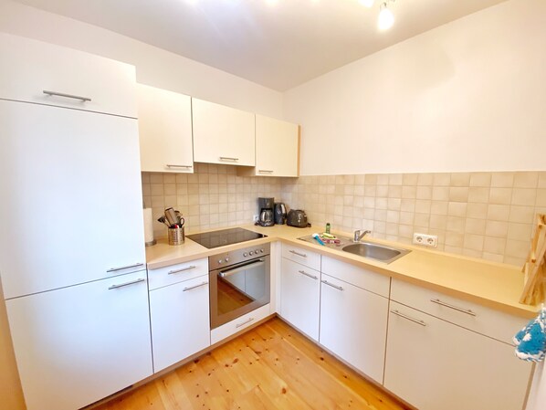 A modern kitchen with white cabinets, a stainless steel sink, and a built-in oven.