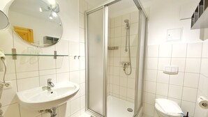 A modern bathroom with a glass-enclosed shower, a sink, and a toilet.