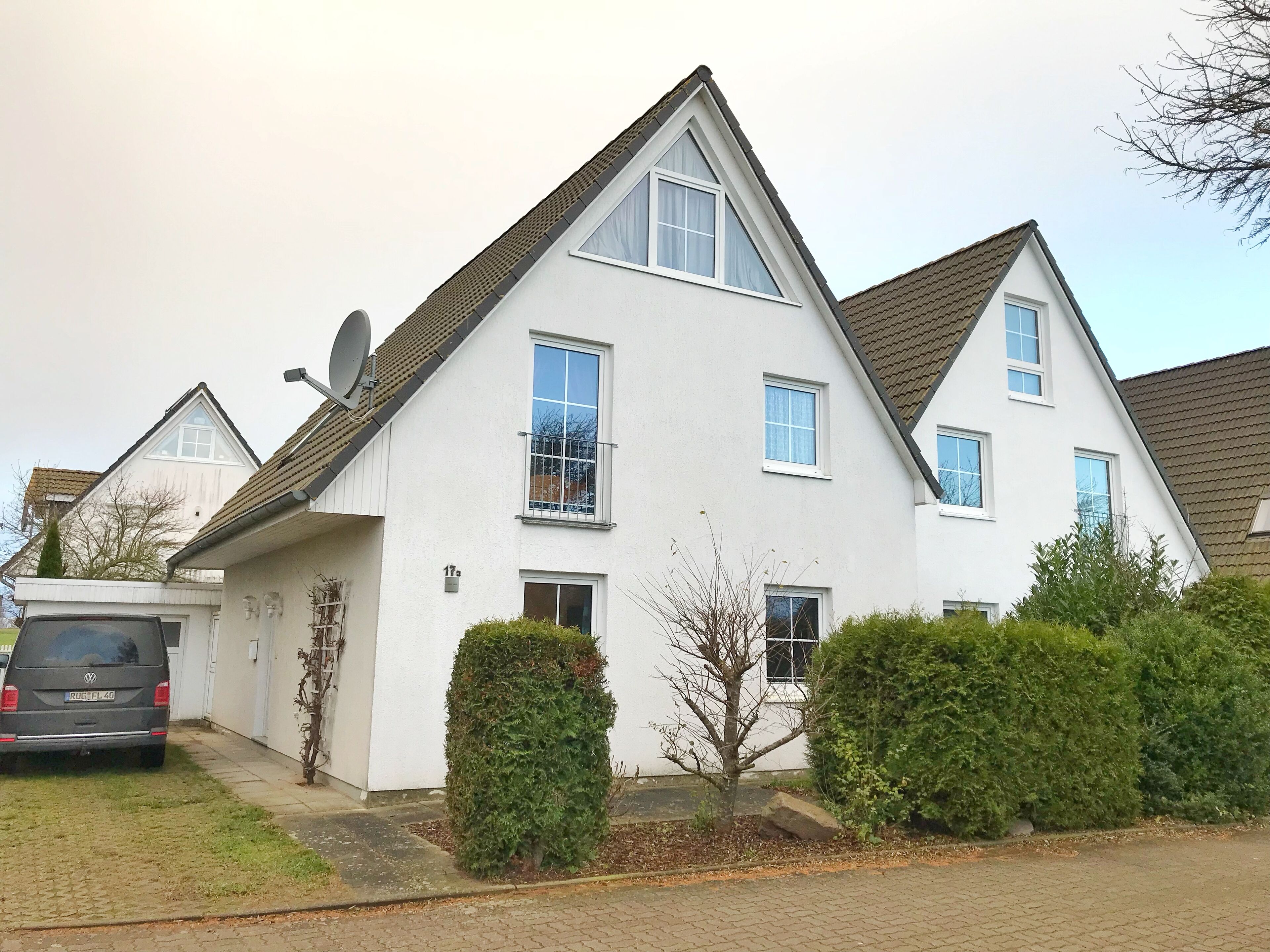 Een wit huis met twee verdiepingen, een schotelantenne, een garage en een oprit.