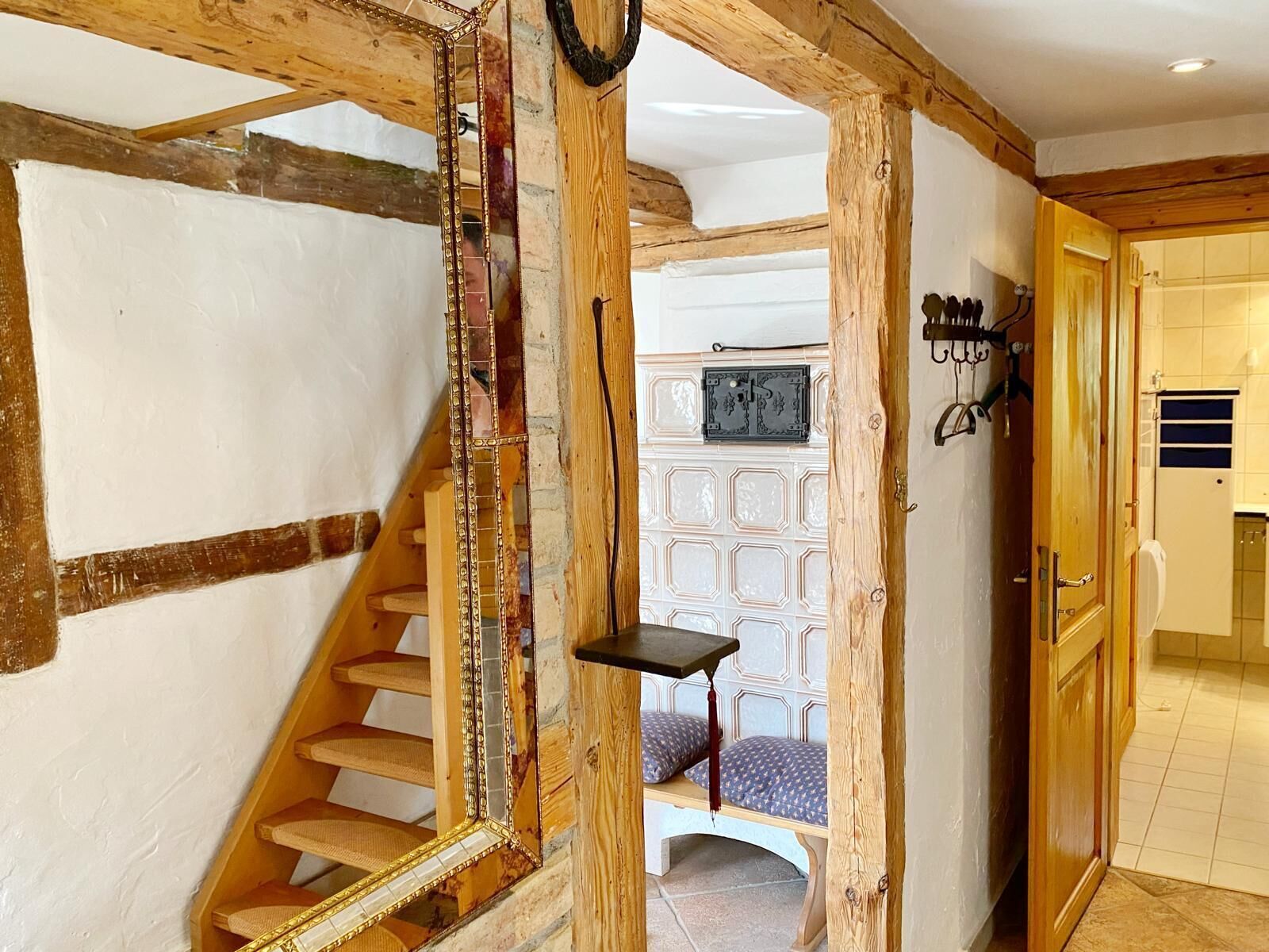 A wooden staircase with a mirror, a small table, and a patterned wall in the background.