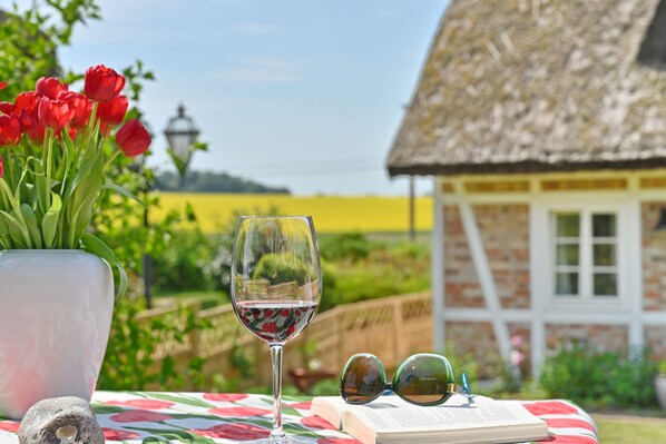 A table with a book, a wine glass, and a vase of red tulips. - Landhaus Vilmnitz, Wohnung 2 (Vilmnitz)