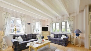 A cozy living room with two plaid sofas, a wooden coffee table, and a television on a cabinet. - Landhaus Vilmnitz, Wohnung 7 (Vilmnitz)