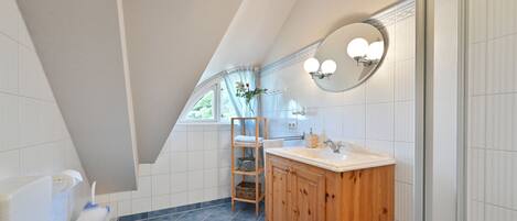 A bathroom with a wooden vanity, a round mirror, and a white toilet.