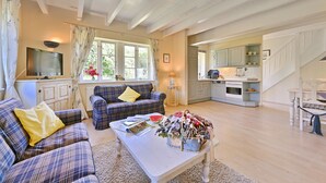 A living room with a sofa, a coffee table, and a television. There is a kitchen area with cabinets and a staircase. - Country house Vilmnitz, apartment 9 (Vilmnitz)