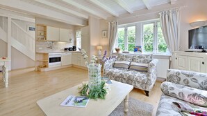 A spacious living area with a sofa, a coffee table with a magazine, and a kitchen in the background. - Landhaus Vilmnitz, Wohnung 10 (Vilmnitz)