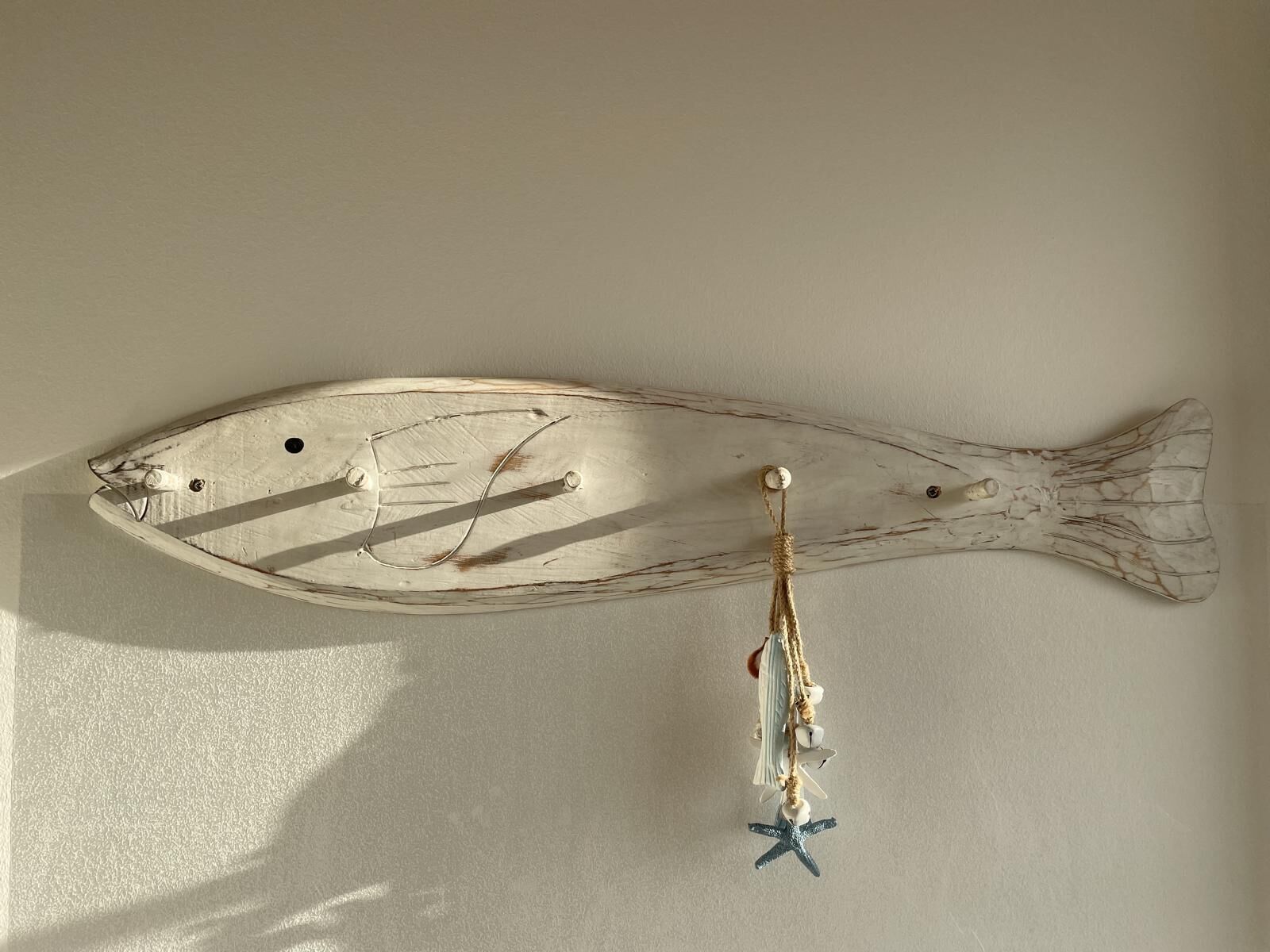 Une décoration murale représentant un poisson, avec un ornement en forme d’étoile de mer suspendu en dessous.