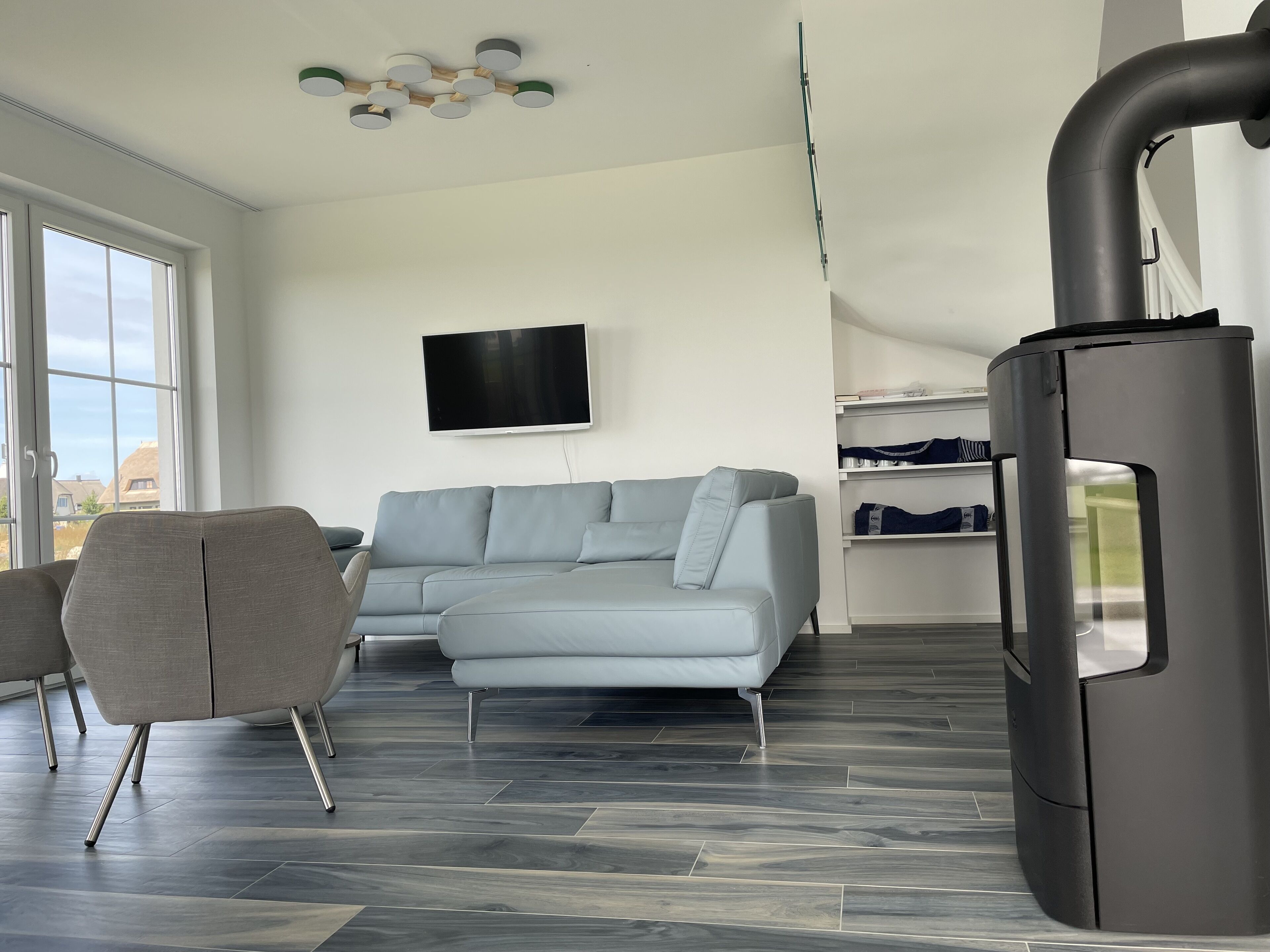 A modern living room with a grey sectional sofa, a flat-screen TV, and a built-in fireplace.