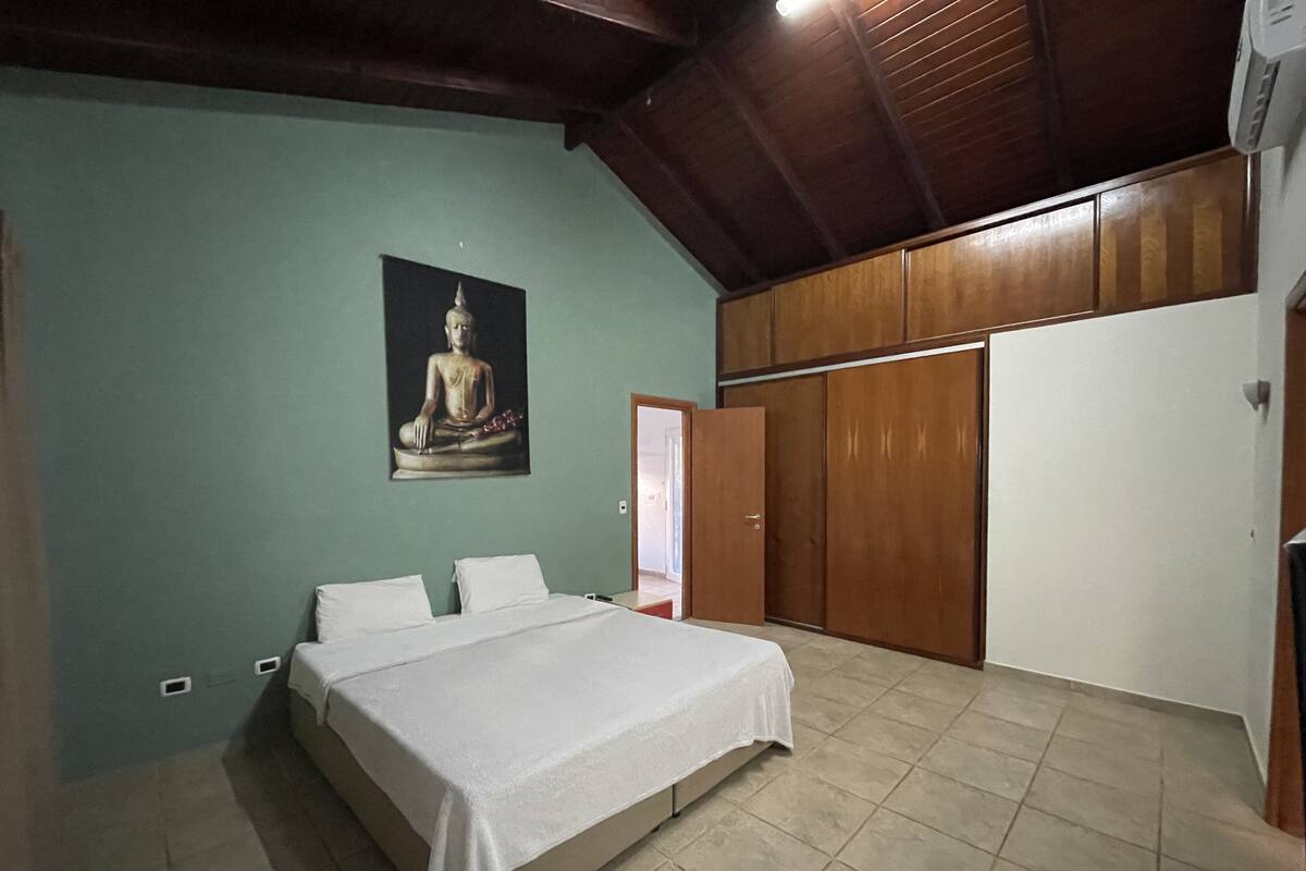 A bedroom with a bed, a wall-mounted Buddha statue, a wardrobe, and a door.