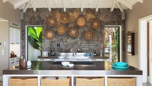 A modern kitchen with a stone backsplash, stainless steel appliances, and woven baskets on the counter. - Il Faro (1/7 Rooms) Luxury villa (Anse des Lezards)