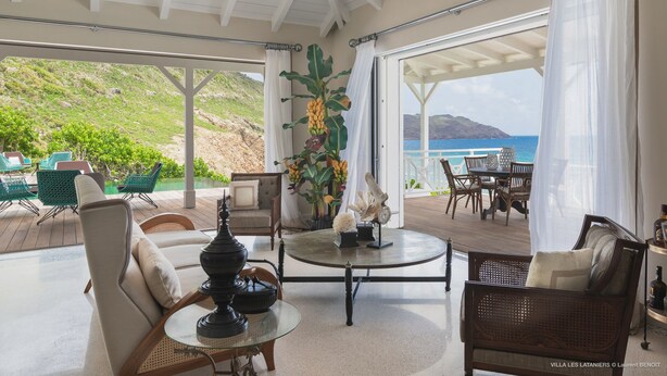 A spacious indoor area with a view of the ocean, furnished with chairs and a table, and decorated with plants and a lamp. - Il Faro (1/7 Rooms) Luxury villa (Anse des Lezards)