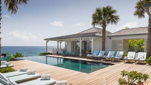 A poolside area with lounge chairs, a covered seating area, and a view of the ocean. - Il Faro (1/7 Rooms) Luxury villa (Anse des Lezards)