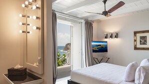 Un dormitorio con una cama grande, un tocador con luces, un televisor y vistas al mar.