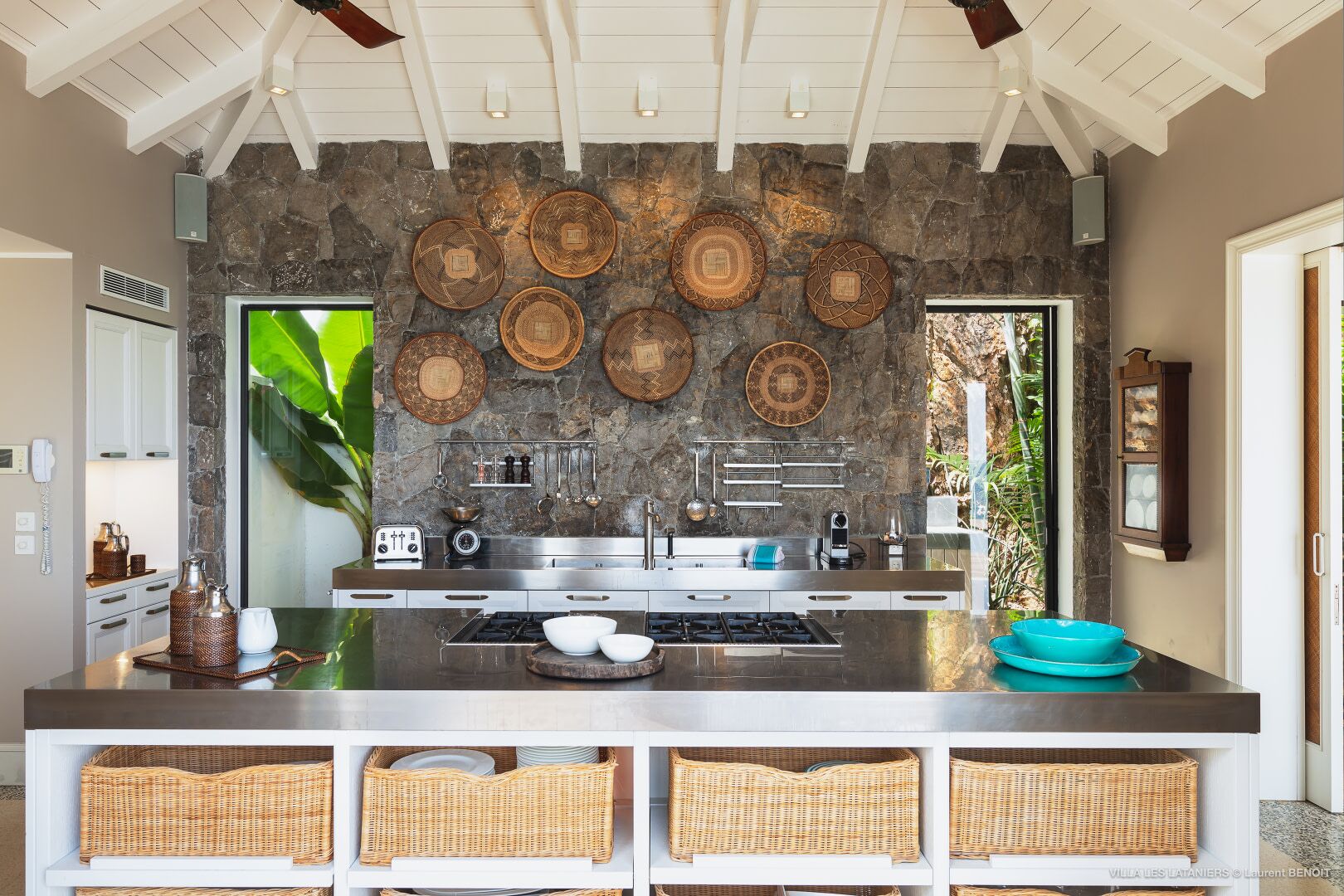A modern kitchen with a stone backsplash, stainless steel appliances, and woven baskets on the counter.